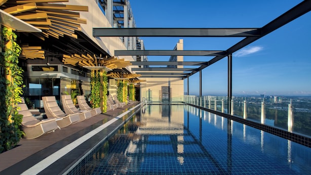 A rooftop infinity pool with lounge chairs and greenery, offering a city view. - St. Giles Southkey (Johor Bahru)