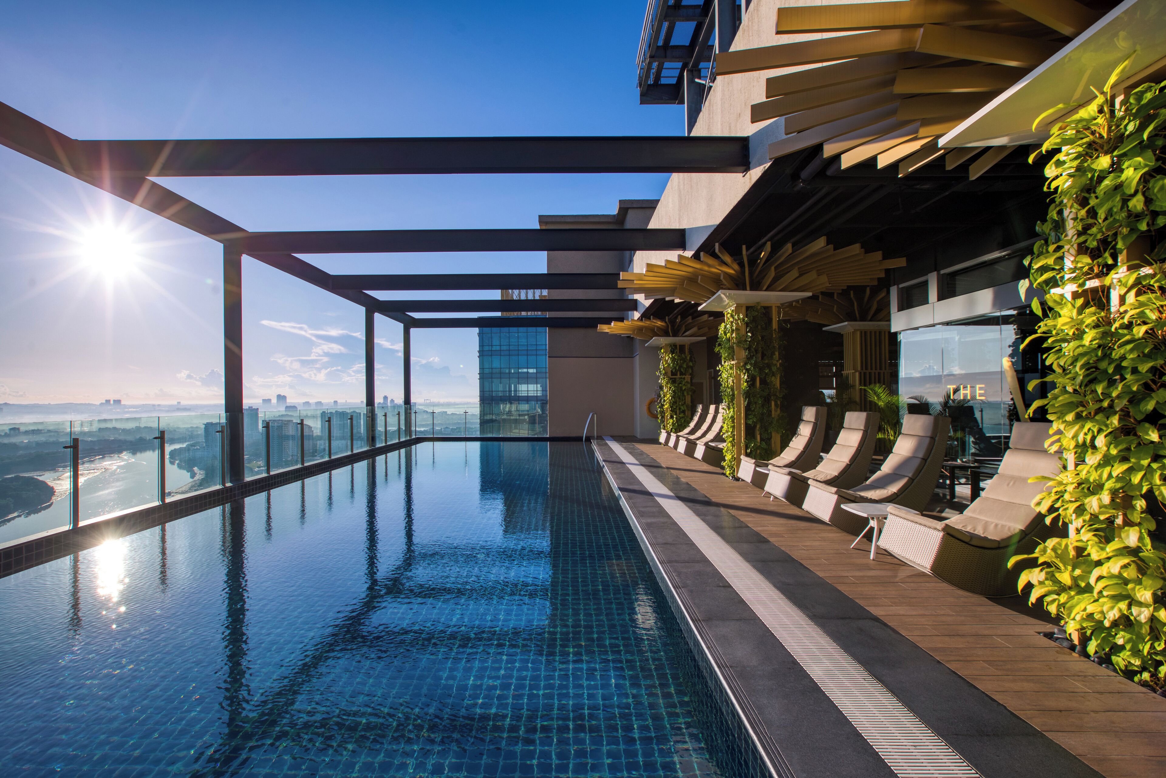 Piscina infinita en la azotea con vistas a la ciudad, arquitectura moderna y mobiliario exterior.
