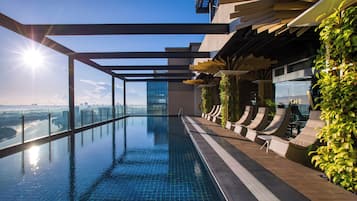 Piscina infinita en la azotea con vistas a la ciudad, arquitectura moderna y mobiliario exterior.