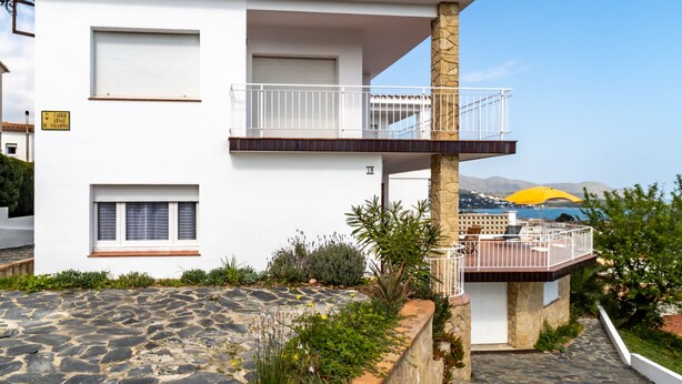 Un edificio de dos plantas con balcón, suelo de piedra y vistas al mar.