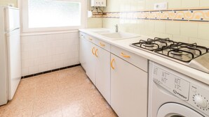 Una cocina con lavadora, estufa y lavabo.