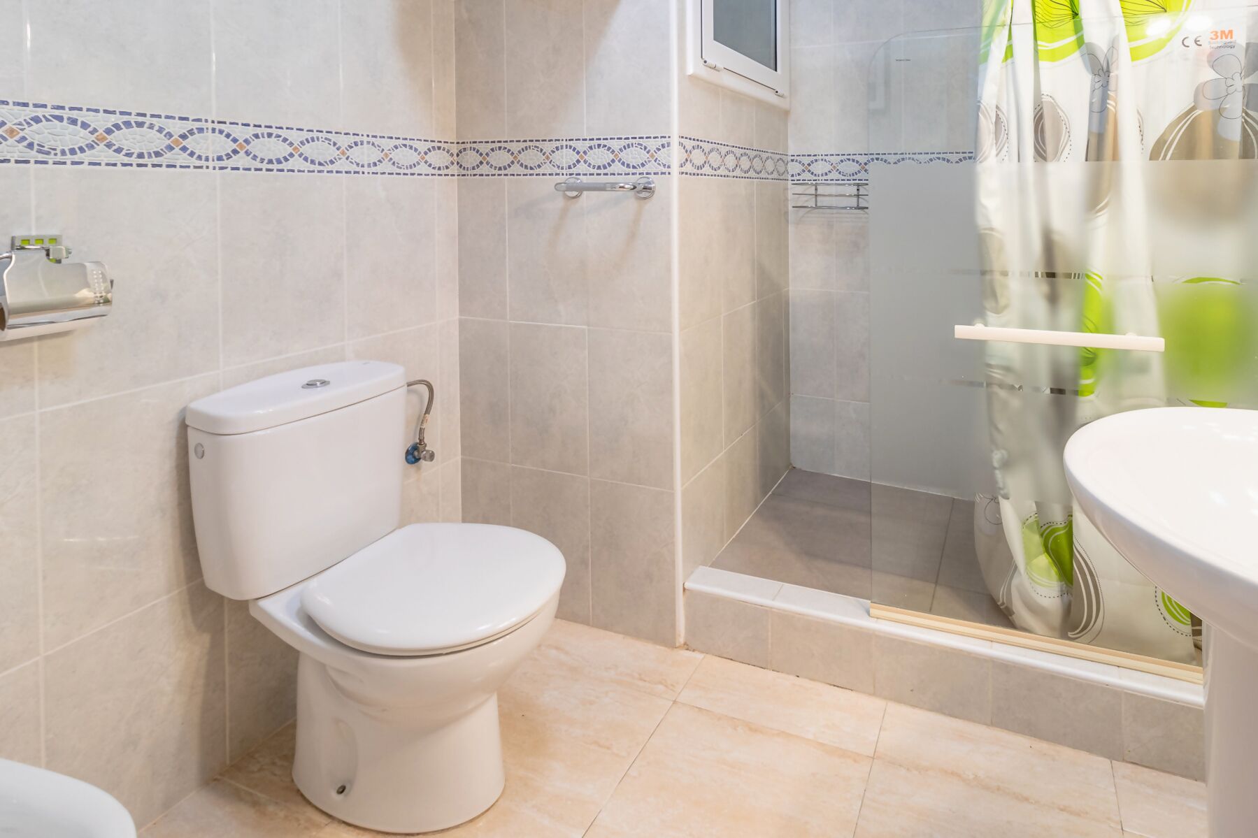 Een badkamer met een toilet, een douche en een wastafel.