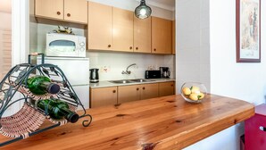 A kitchen with wooden cabinets, a microwave, a sink, a coffee maker, and a bowl of lemons on the counter. - Sant Carles 24 - apartment with terrace (Llança)