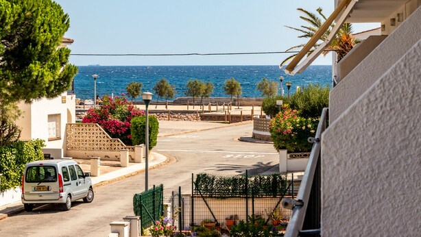 A coastal street with a white van parked on the side, a stop sign, and a view of the sea. - Sant Carles 25 - apartment with terrace (Llança)