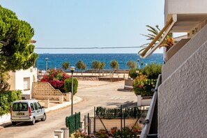 A coastal street with a white van parked on the side, a stop sign, and a view of the sea. - Sant Carles 25 - apartment with terrace (Llança)