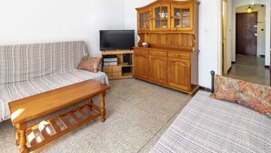 A living room with a sofa, a wooden coffee table, a television, and a wooden cabinet. - Sant Genís 19 - top-floor apartment with terrace (Llança)