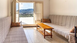 A living room with a sofa set, a wooden coffee table, and a view of a mountainous landscape through a large window. - Sant Genís 19 - top-floor apartment with terrace (Llança)