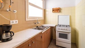 A compact kitchen with a stove, sink, and window. - Sant Genís 19 - top-floor apartment with terrace (Llança)