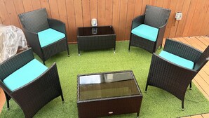A patio area with wicker furniture, including chairs and a table, set on artificial grass. - Key Largo New Construction 2-story! Exclusive Rights for 28 Days! (Key Largo)