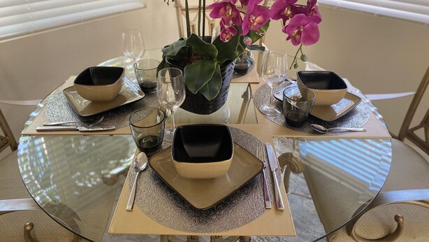 A round glass table set for a meal with black and white bowls, cutlery, and clear glasses. - Key Largo New Construction 2-story! Exclusive Rights for 28 Days! (Key Largo)