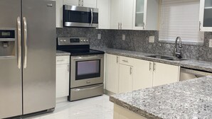 A modern kitchen with stainless steel appliances, white cabinetry, and granite countertops. - Key Largo New Construction 2-story! Exclusive Rights for 28 Days! (Key Largo)