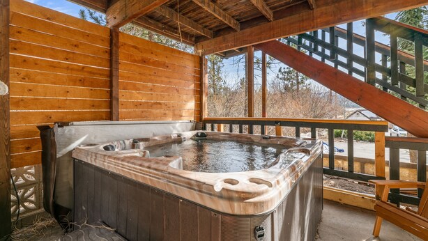 Eine Holzterrasse mit Whirlpool, Holelllaufgeländern und Blick auf die umliegenden Bäume.
