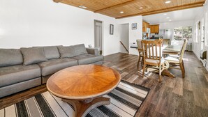 Ein Wohnzimmer mit grauem Sofa, einem Holztisch und einem Streifen Teppich.