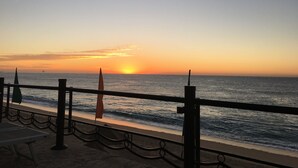 A sunset view from a beachside promenade with a railing, a flag, and a distant ship on the horizon. - Luxury resort on the beach - walking to downtown (Cabo San Lucas)