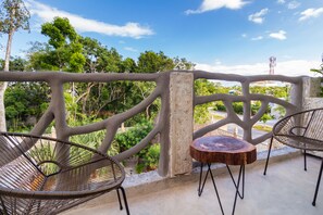 A balcony with a wrought iron railing, two wicker chairs, and a small round table. - Jaakbal Tulum (Tulum)
