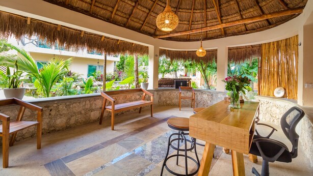A restaurant with a thatched roof, wooden furniture, and a view of lush greenery outside. - Jaakbal Tulum (Tulum)