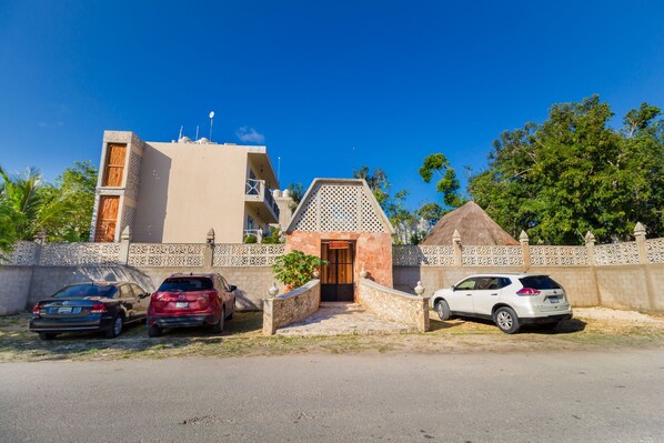 A building with a central entrance, a small adjacent structure, and a thatched-roof building. There are three cars parked in front. - Jaakbal Tulum (Tulum)
