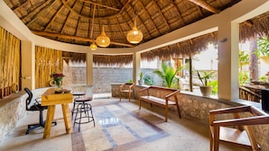 A room with a thatched roof, wooden furniture, and potted plants. - Jaakbal Tulum (Tulum)
