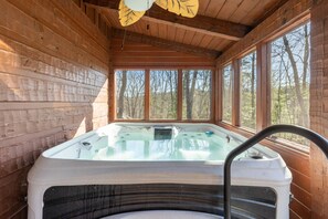Relax in the hot tub under the cabin's high ceiling with a view of the surrounding forest.