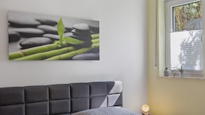 A bedroom with a headboard, pillows, a bedside table with a lamp, and a window with blinds. - Apartment 'Fuldatalblick' with Garden & Wi-Fi (Fulda)