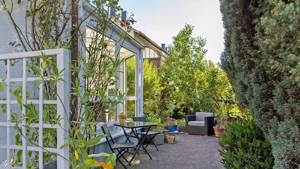 A patio with outdoor furniture, a white fence, and various plants. - Apartment 'Fuldatalblick' with Garden & Wi-Fi (Fulda)