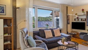 A modern living room with a sofa, armchair, and a coffee table. - Apartment 'Fuldatalblick' with Garden & Wi-Fi (Fulda)