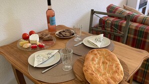 Ett matbord i trä med en vinflaska, ost, bröd och ett glas vatten.