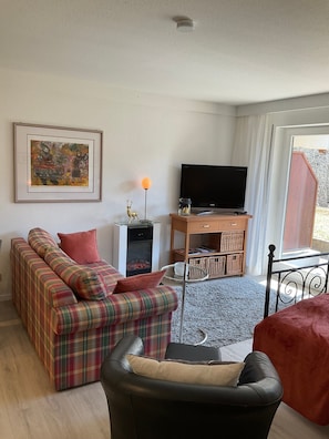 Una sala de estar con un sofá, televisor, chimenea y un cuadro en la pared.