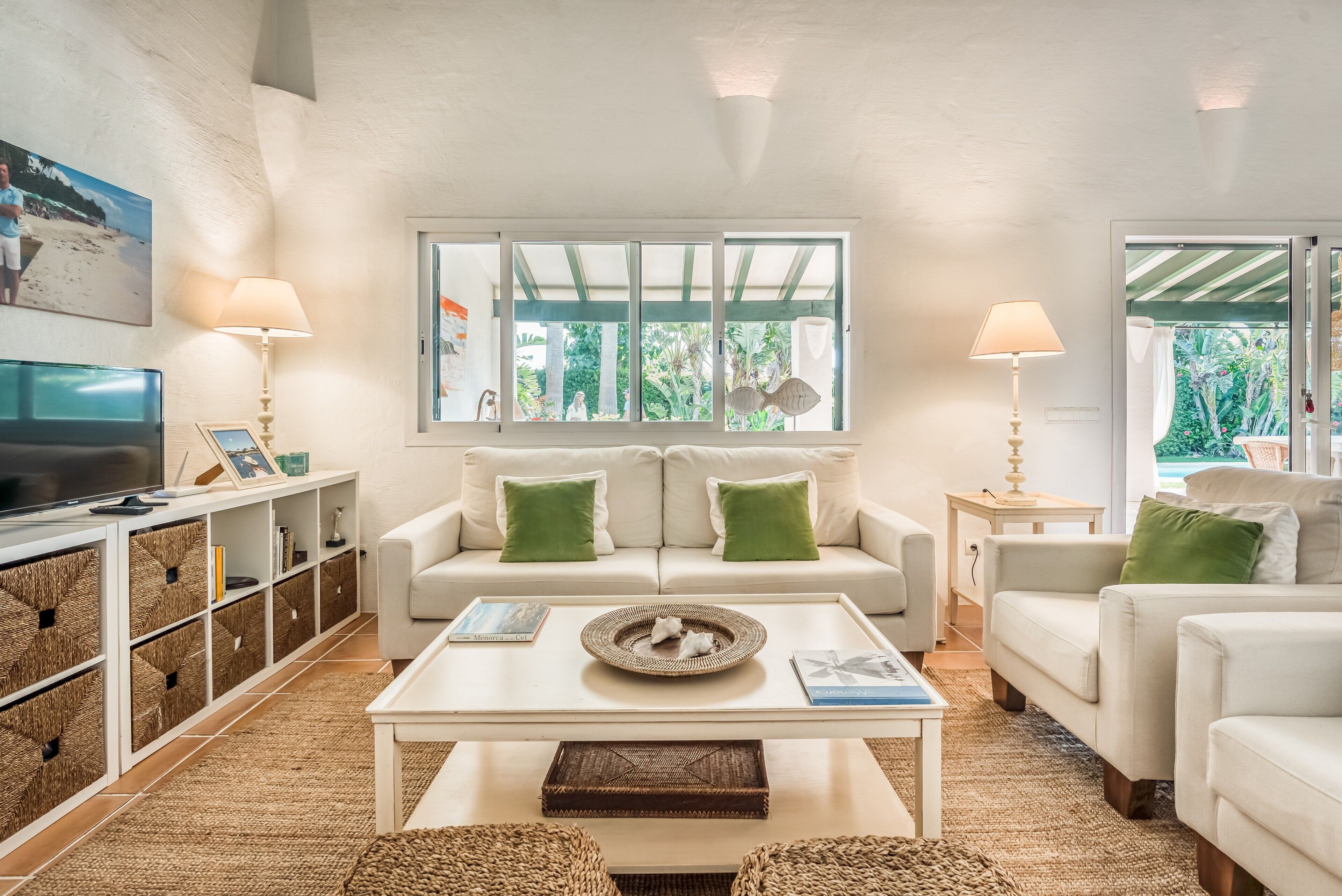Un salón con sofá, mesa de centro, televisor y ventana con vistas a zonas verdes.