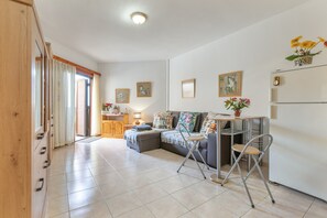 Een ruime woonkamer met een bank, een eettafel en een keukenhoek.