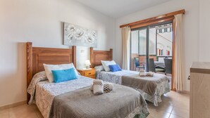 Una camera d'albergo con due letti, una testiera in legno, un comodino, una lampada e vista all'esterno.