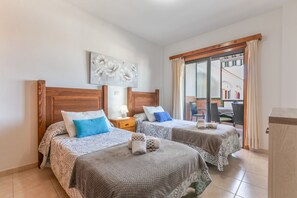 Ein Hotelzimmer mit zwei Betten, einem Holzkopfteil, einem Nachttisch, einer Lampe und Blick nach außen.