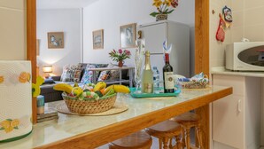 Una cucina con un cesto di frutta, bottiglie di vino e un forno a microonde.