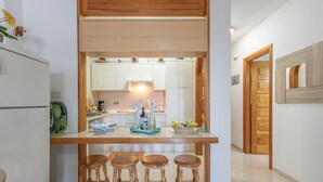 Una cucina con un piano di lavoro in legno, tre sgabelli e mobili bianchi.
