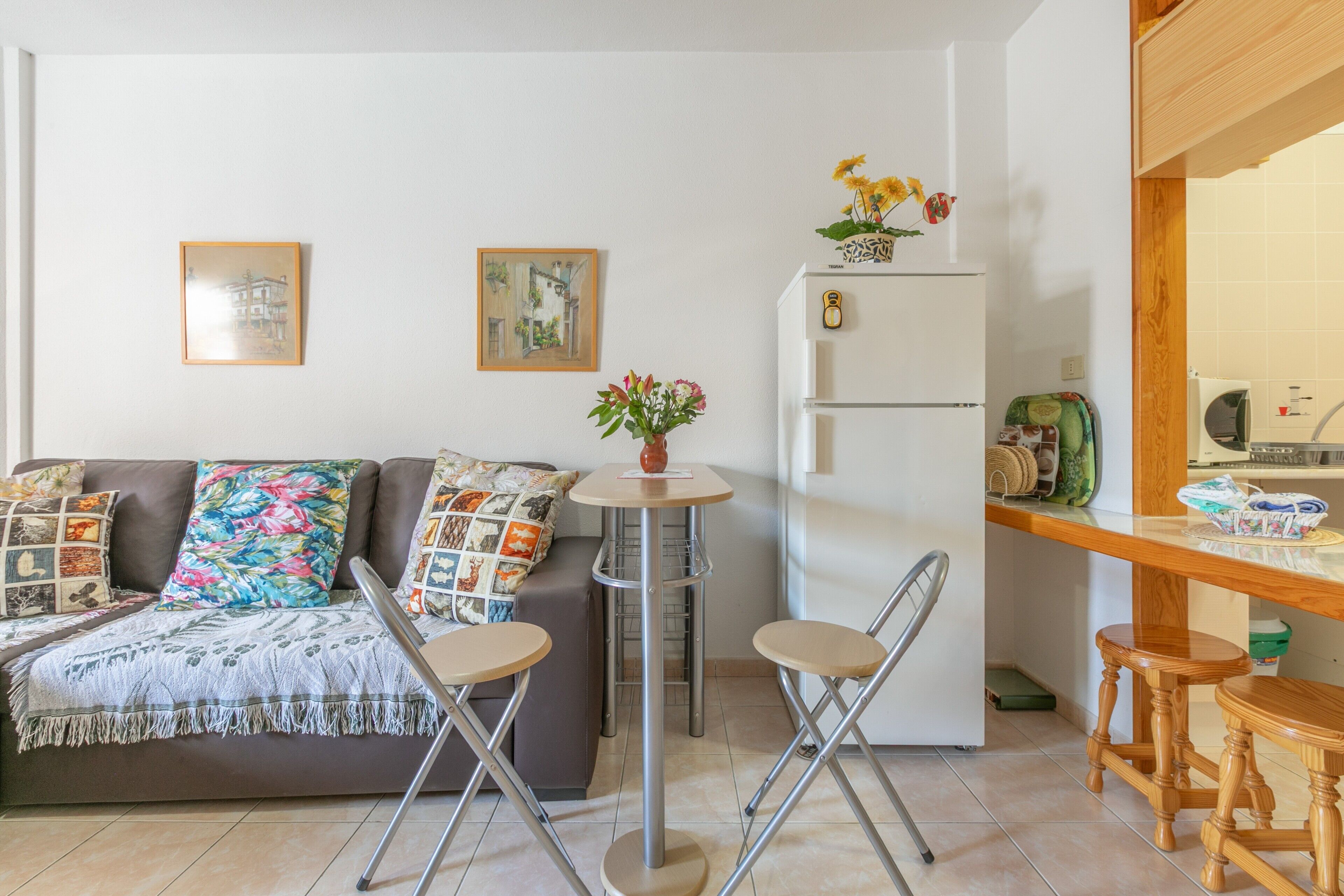Un salón con sofá, dos sillones, una mesita redonda, un refrigerador y un microondas.