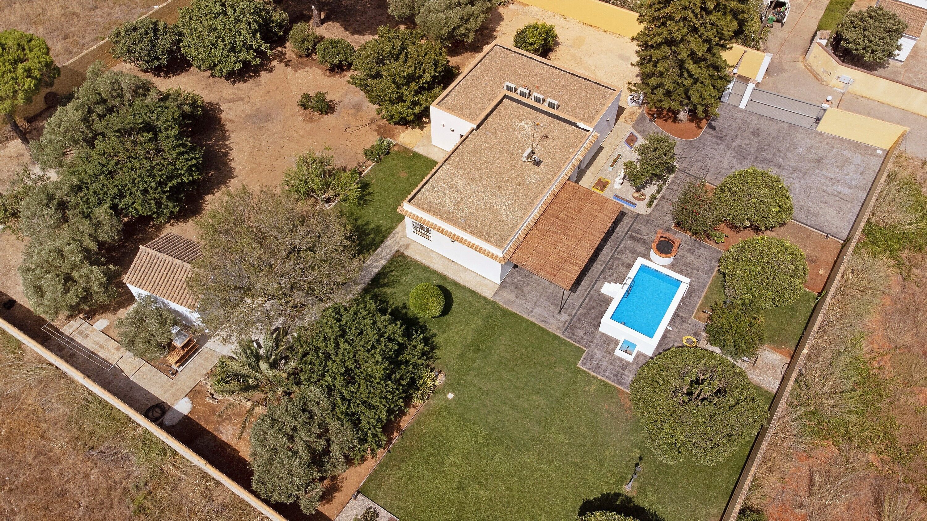 An aerial view of a residential property with a swimming pool, a detached garage, and a well-maintained lawn.