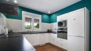 A kitchen with white cabinets, a black countertop, a microwave, and a refrigerator. - Holiday Home La Alberca with Pool, Garden and Wi-Fi (Chiclana de la Frontera)