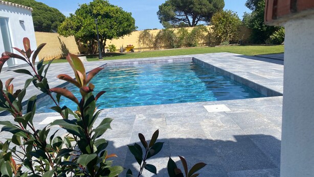 A rectangular swimming pool with clear blue water, surrounded by stone tiles. - Holiday Home La Alberca with Pool, Garden and Wi-Fi (Chiclana de la Frontera)