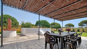 An outdoor patio with a covered seating area, a brick wall, and a view of trees. - Holiday Home La Alberca with Pool, Garden and Wi-Fi (Chiclana de la Frontera)