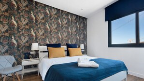 Une chambre d’hôtel moderne avec un grand lit, une table de chevet, une chaise et une fenêtre donnant sur un beau paysage.