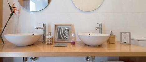Een badkamer met twee grote ronde spiegels, een houten wastafelmeubel, twee wastafels en een decoratieve plant.