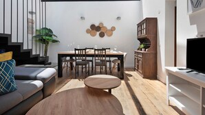 Un salon moderne avec un canapé, une table ronde, un coin repas et un téléviseur.