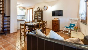 Un comedor con una mesa y sillas de madera, un televisor y un reloj en la pared.