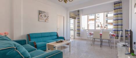 Una sala de estar con un sofá azul, una mesa de centro blanca y una araña.
