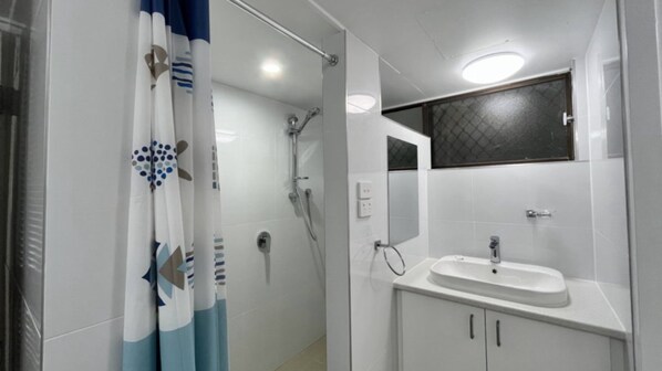 A bathroom with a shower, a sink, and a mirror.