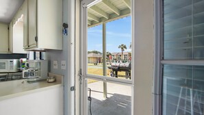 A kitchen with a microwave, coffee maker, and a view of a barbecue grill outside. - Your Beach Getaway Awaits YOU! (Panama City Beach)