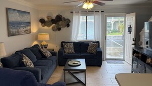 A living room with a dark blue sofa, a coffee table, and a ceiling fan. - Your Beach Getaway Awaits YOU! (Panama City Beach)