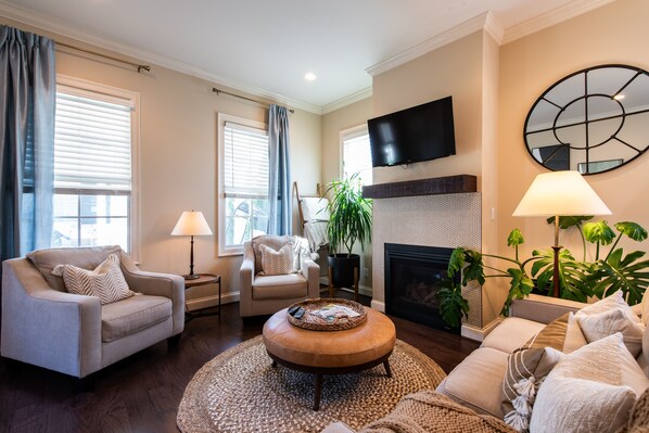 A living room with a sofa, armchair, and a coffee table. There is a fireplace, a television, and a large plant. - ❤️Stay at Peppermint Cottage - Norton Commons -Walk eat & shop- free breakfast (Prospect)