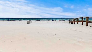 A beach with a wooden pier extending into the water, sandy beach, and clear blue sky. - Harbor House 2BR 2BA Gulf-View 1st floor Wrap Balcony Pool King Bed (Gulf Shores)