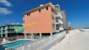 A beachfront hotel with a pool, a sandy beach, and a clear blue sky. - Harbor House 2BR 2BA Gulf-View 1st floor Wrap Balcony Pool King Bed (Gulf Shores)